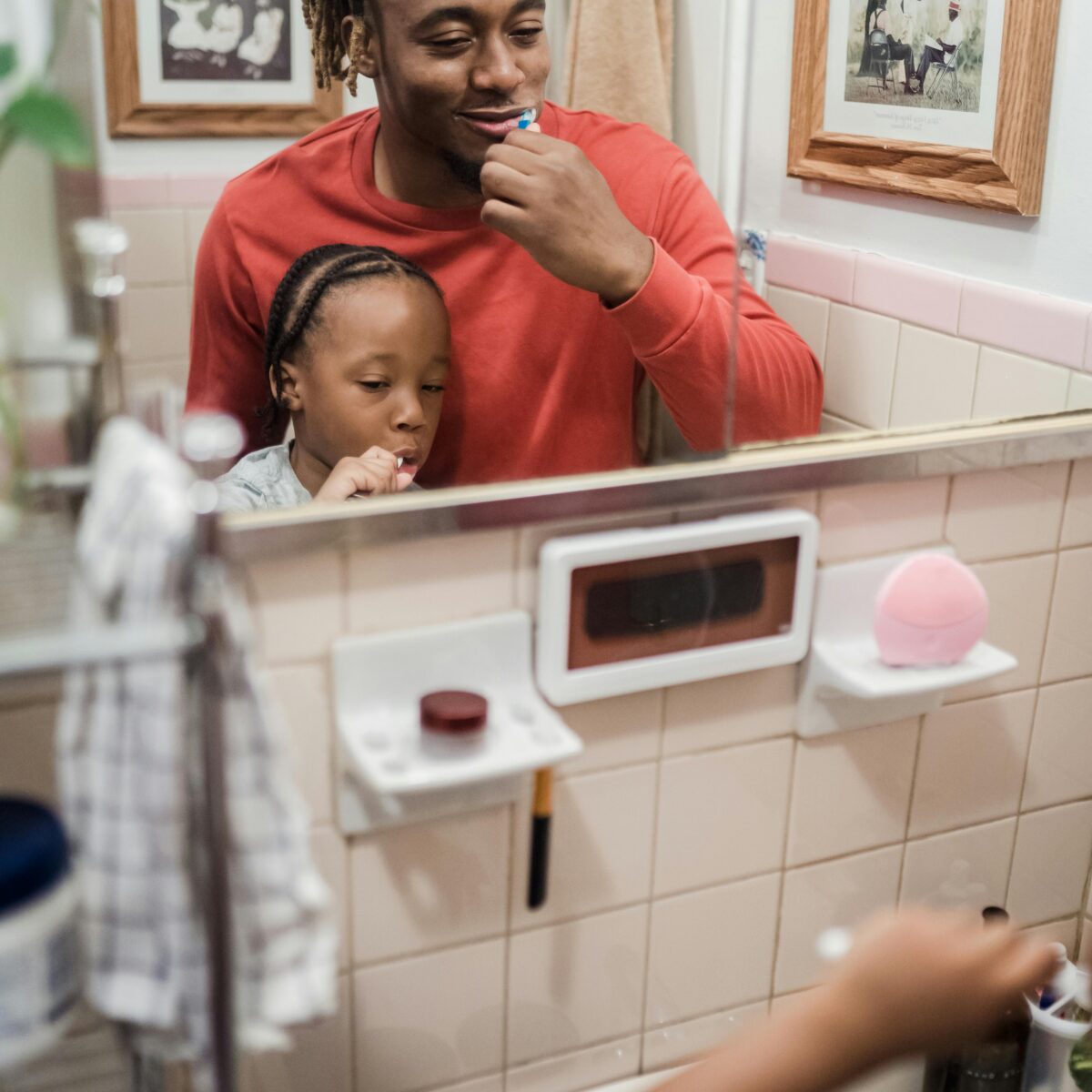 Father and young child brushing their teeth together in a bathroom, sharing a calm everyday routine