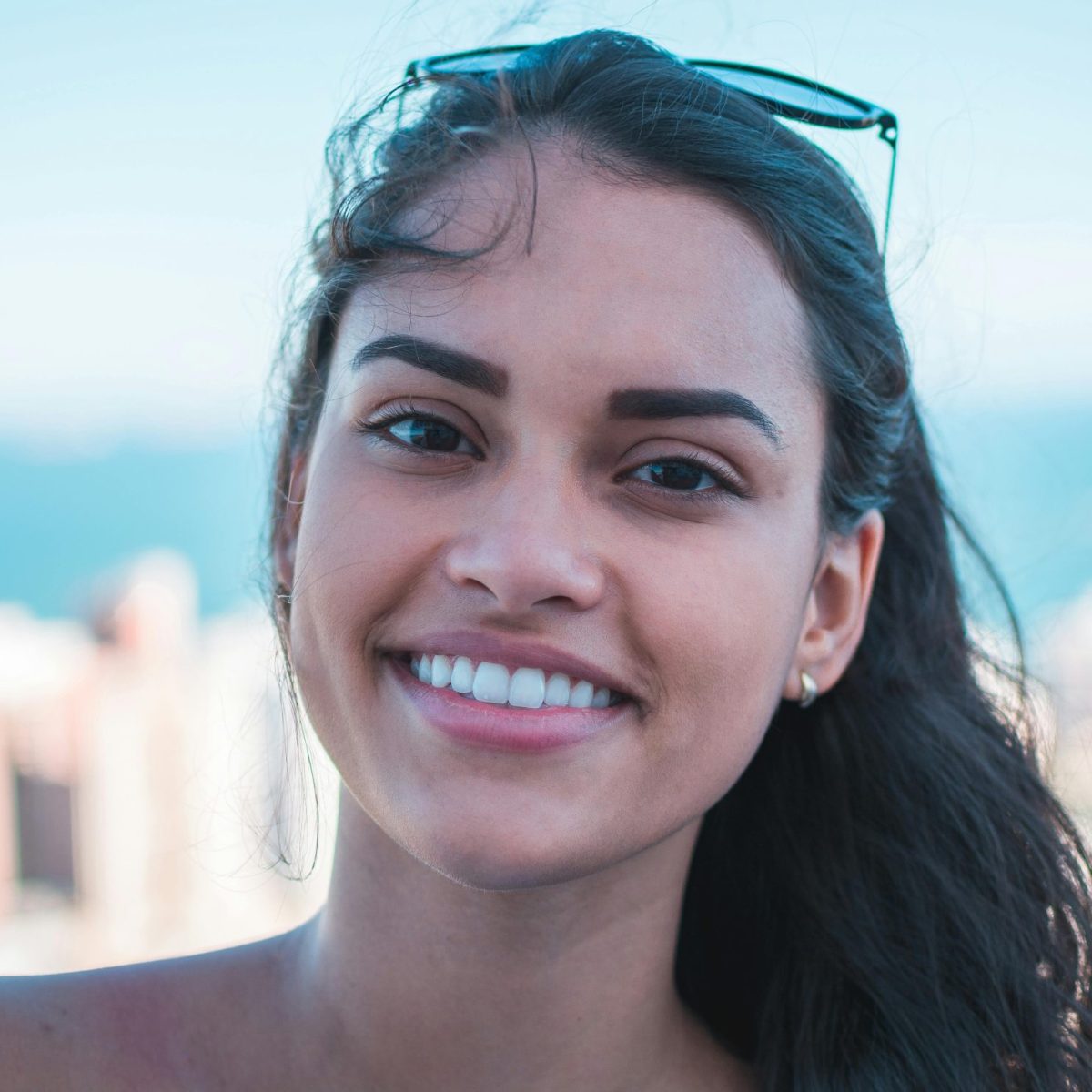 Woman smiling naturally outdoors with a cityscape and water in the background