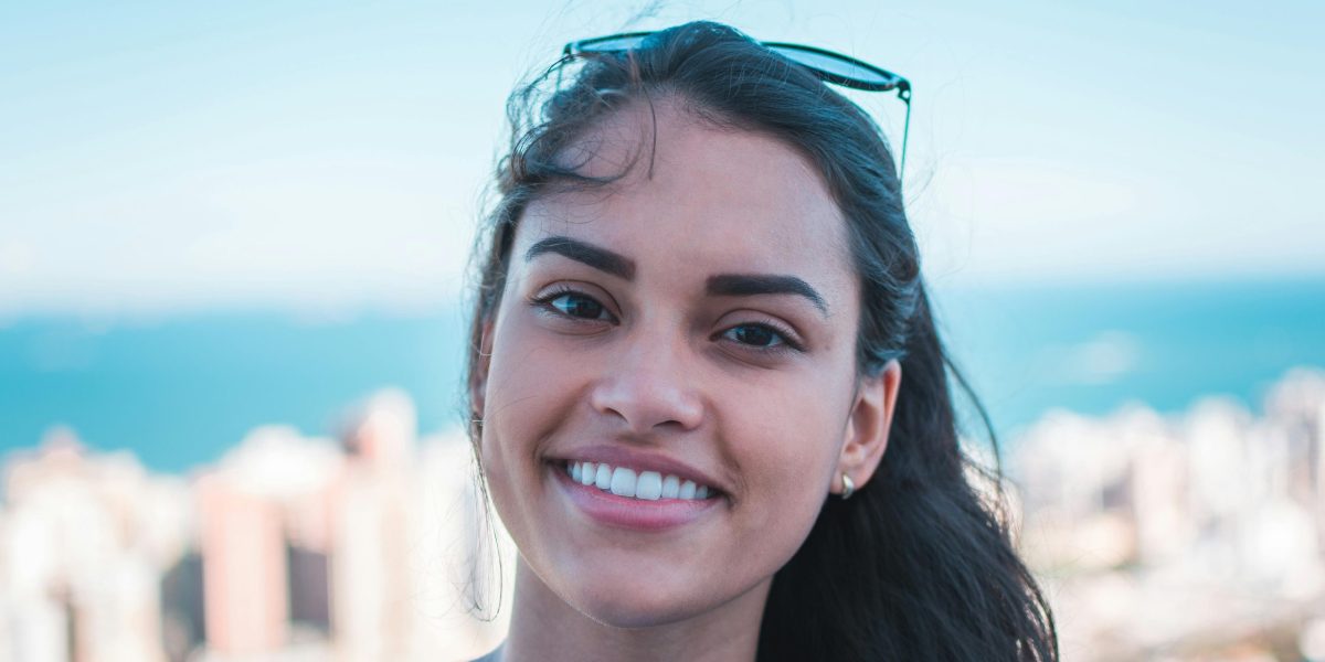 Woman smiling naturally outdoors with a cityscape and water in the background