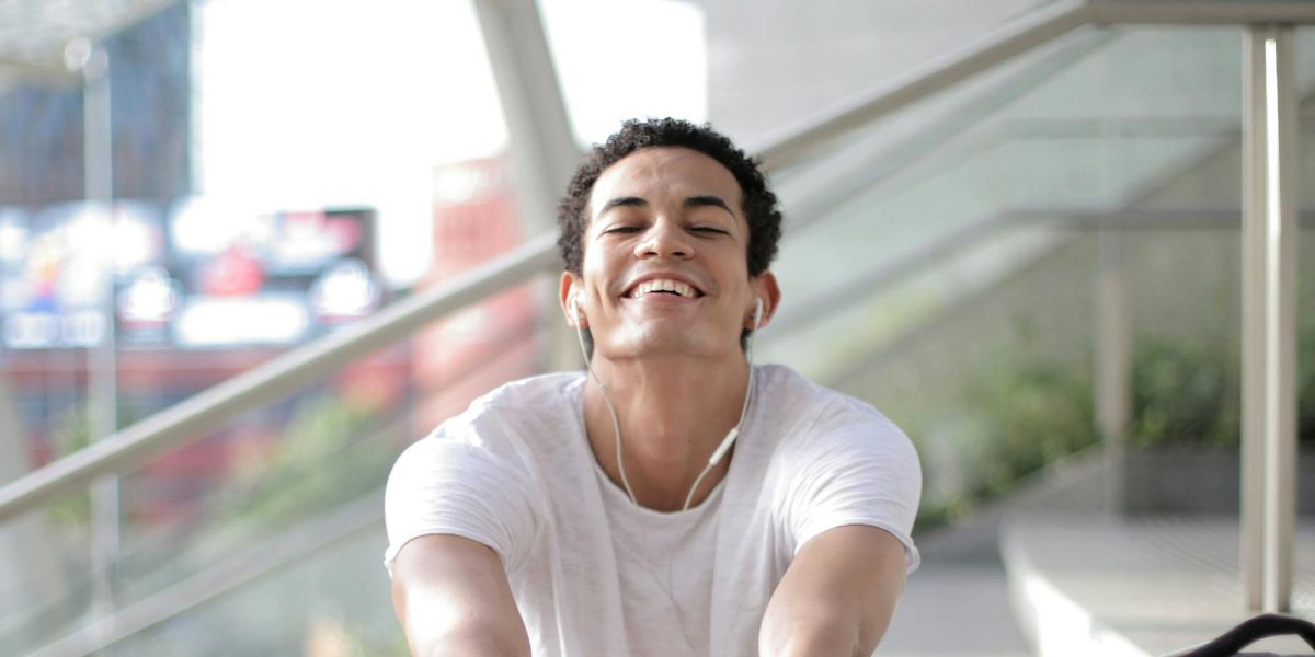 Young man stretching on outdoor steps, smiling comfortably during a casual workout break