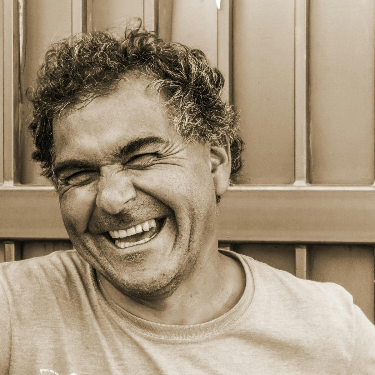 Man laughing with a relaxed, natural smile, captured in a candid portrait outdoors