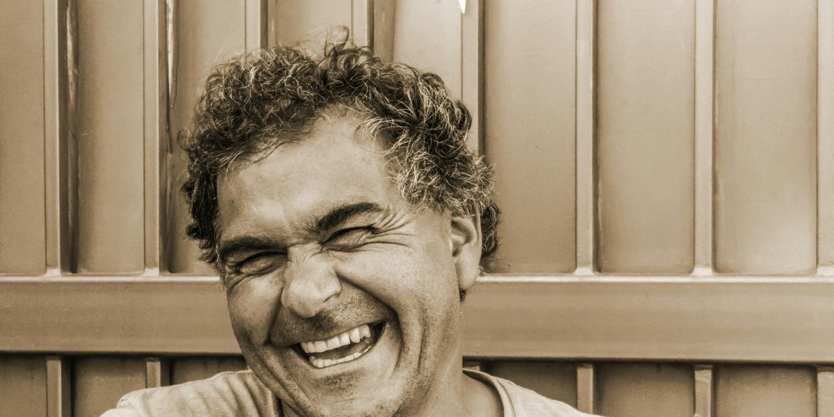 Man laughing with a relaxed, natural smile, captured in a candid portrait outdoors