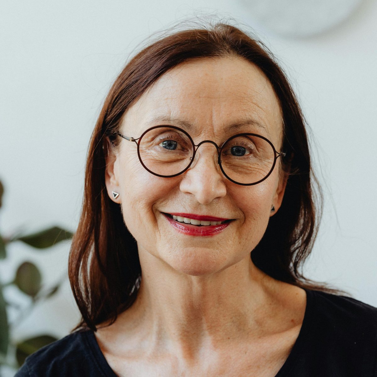 Older woman wearing glasses and smiling gently indoors, captured in soft natural light